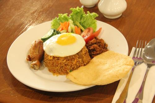 a plate of food with an egg and vegetables on a table at Dreamtel Jakarta in Jakarta