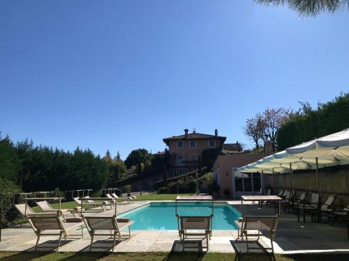 a pool with chairs and tables and a house at Villa Bricco dei Cogni in La Morra