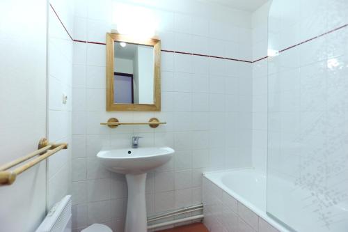 a white bathroom with a sink and a mirror at Vacancéole - Résidence Tyrol in Les Deux Alpes