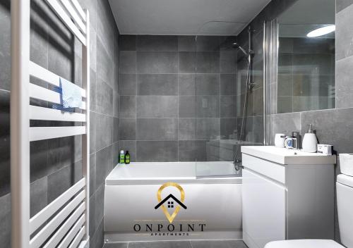 a bathroom with a white tub and a sink and a toilet at OnPoint - Spacious 2 Bed Apt - FREE Parking in Reading