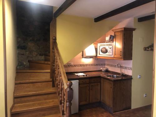 una cocina con escalera con fregadero y microondas en Apartamentos y Casas de Aldea La Pornacal, en Villar de Vildas