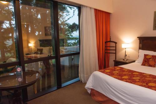 a hotel room with a bed and a large window at Hotel Casino Acaray in Ciudad del Este