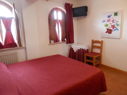 a bedroom with a red bed and two windows at Hotel Villa Stella in Cascia