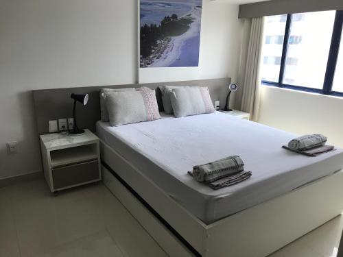 a white bedroom with a large bed with a phone on it at Studio Everest Flats in Recife
