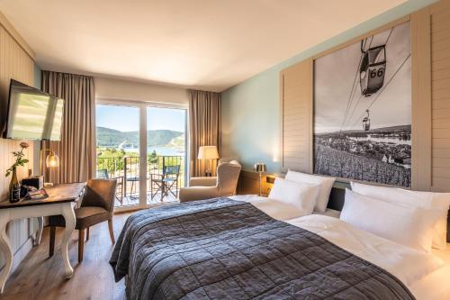 a hotel room with a bed and a desk and a window at PAPA RHEIN - Hotel & Spa in Bingen am Rhein