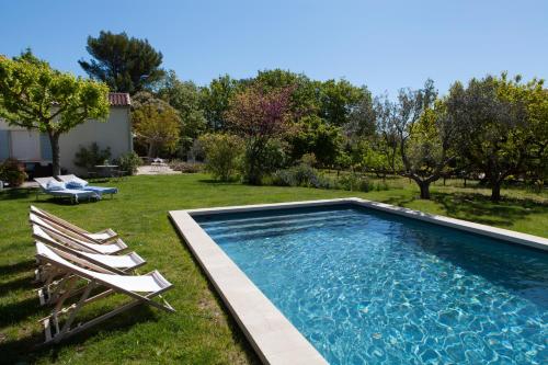 a swimming pool in a yard with two lawn chairs at Chambre d'hôtes le Mirail in La Motte-dʼAigues