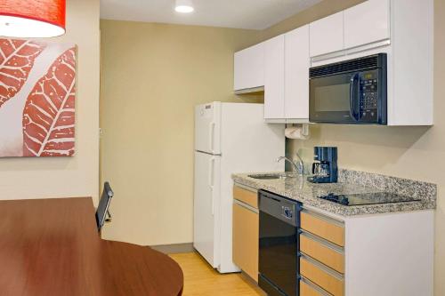 a kitchen with a white refrigerator and a table at MainStay Suites Chicago Hoffman Estates in Hoffman Estates