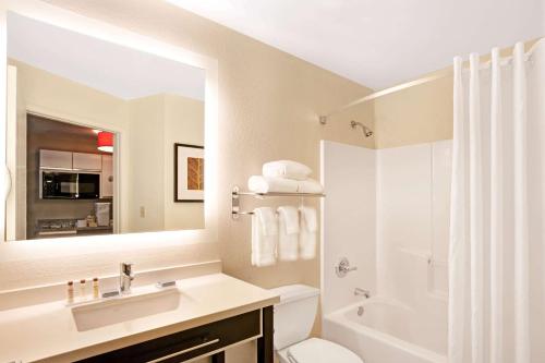 a bathroom with a sink and a toilet and a mirror at MainStay Suites Chicago Schaumburg in Schaumburg