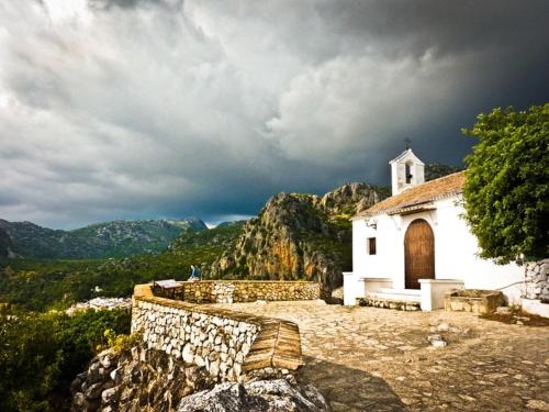 a small white church on a mountain under a cloudy sky at Alvarado Loft Rural in Ubrique