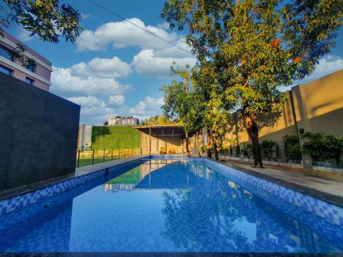 a blue swimming pool with a tree and a building at The Orchid Lonavala in Lonavala