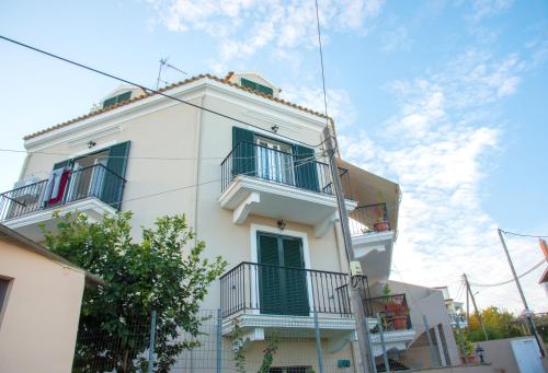 a white building with green doors and balconies at Corfu Don Camillo Apartment in (( Agía Eleoúsa ))