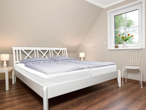 a white bedroom with a white bed and a window at Haus LEE in Kaltenhof