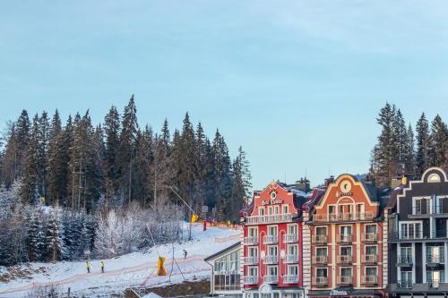 een groep gebouwen in de sneeuw met bomen bij Petros Hotel in Boekovel