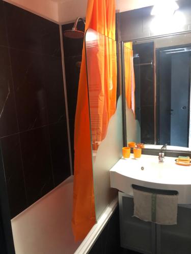 - un rideau de douche orange dans la salle de bains pourvue d'un lavabo dans l'établissement Avoriaz appartement 4pers plein sud skis aux pieds, à Morzine