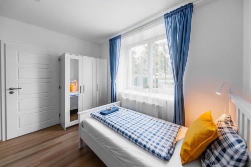 a bedroom with a bed with blue curtains and a window at Chalupa Na Dědině in Dolní Dunajovice