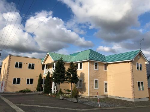 a house with a green roof on a street at Alpine Guesthouse in Furano
