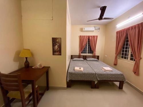 1 dormitorio con cama, mesa y escritorio en Gloria Homestay en Kochi