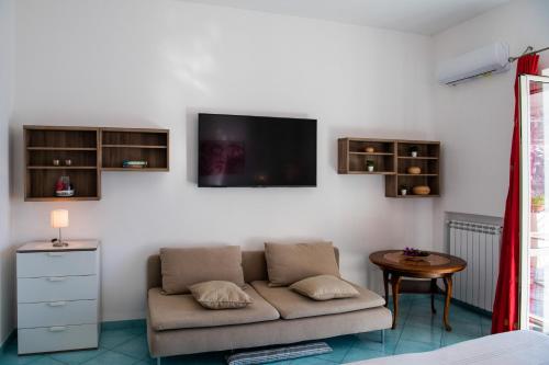a living room with a couch and a tv on the wall at Casa Gilda Positano in Positano