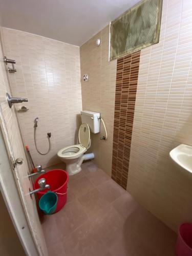 a bathroom with a toilet and a sink and a bucket at Gloria Homestay in Cochin