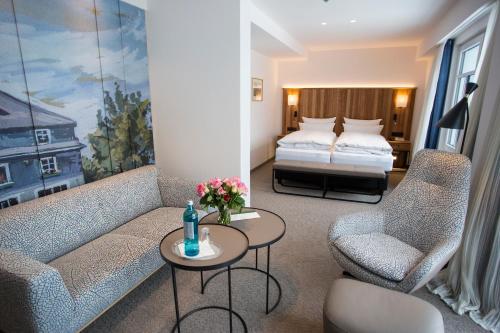 een woonkamer met een bank, 2 stoelen en een bed bij Hotel Jagdhaus Wiese in Schmallenberg