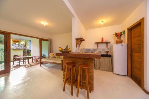 a kitchen with a white refrigerator and wooden stools at Charm Bahia Residencias in Arraial d'Ajuda