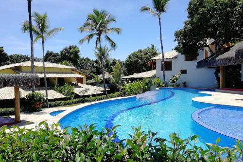 a swimming pool in a resort with palm trees at Charm Bahia Residencias in Arraial d'Ajuda