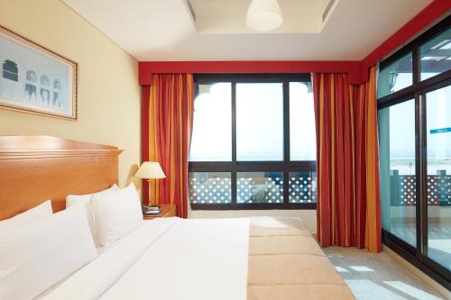 sypialnia z łóżkiem i dużym oknem w obiekcie Roda Beach Resort w Dubaju