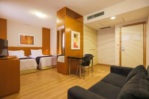 a hotel room with a bed and a couch at Nobile Suítes Uberlândia in Uberlândia