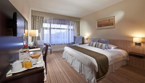 a hotel room with a bed and a desk with a television at The Peninsula Hotel in Vale