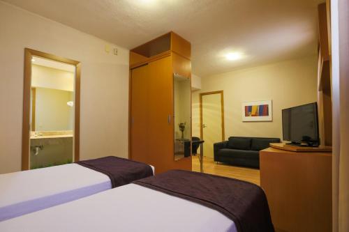a hotel room with two beds and a flat screen tv at Nobile Suítes Uberlândia in Uberlândia