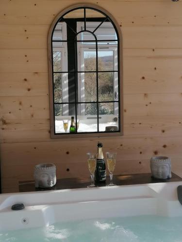 a bath tub with two glasses and a window at Le gîte du Moulin in Lagardelle-sur-Lèze