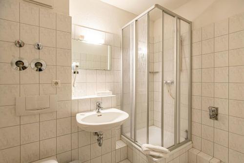 La salle de bains est pourvue d'un lavabo et d'une douche. dans l'établissement Hotel Rostock West im "Kritzmow Park", à Rostock