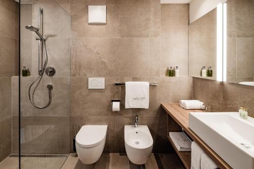 a bathroom with a toilet and a sink and a shower at Sporthotel Obereggen in Obereggen