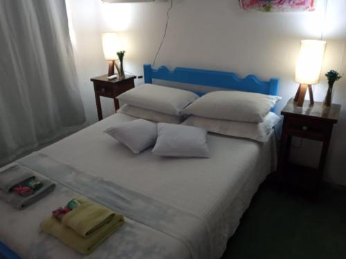 a large white bed with pillows and towels on it at Porão reformado no centro de Floripa in Florianópolis