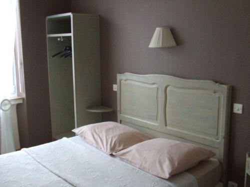 a bed with a white headboard in a bedroom at Hotel Du Centre in Hagondange