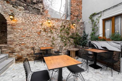 d'une terrasse avec des tables et des chaises à côté d'un mur en briques. dans l'établissement Castillo Rojo Hotel Istanbul, à Istanbul