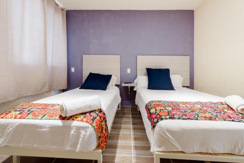 two beds in a room with purple walls at Hotel Hai Do in Bernal