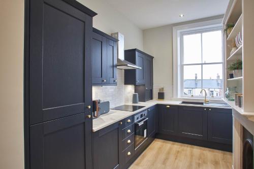 a kitchen with navy blue cabinets and a window at Host & Stay - Huntcliff View Apartment in Saltburn-by-the-Sea