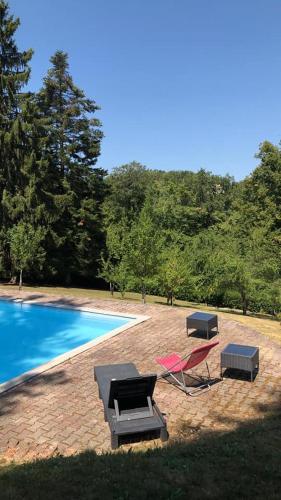 a swimming pool with a table and chairs next to it at Chateau de Bonnevaux in Villeneuve-de-Marc