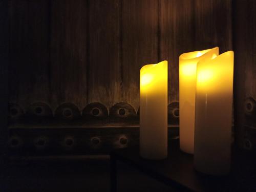 three lit candles sitting on a table in the dark at Alvarado Loft Rural in Ubrique