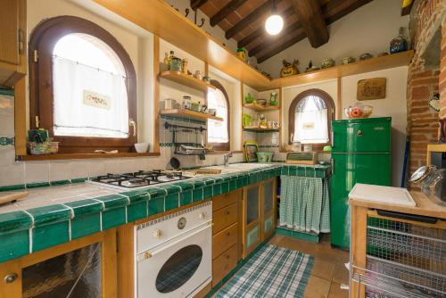 cocina con fogones y nevera verde en Villa Girasole - Homelike Villas, en Lucignano