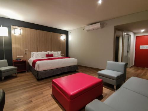 a hotel room with a bed and a red ottoman at Ramada Encore by Wyndham Monterrey Apodaca Zona Aeropuerto in Monterrey