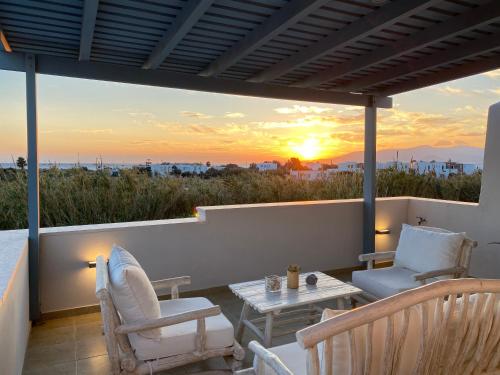 a patio with chairs and a table and a sunset at Seaside Naxos • Holiday Villas in Plaka