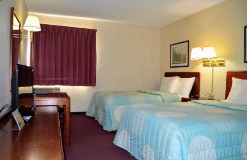 a hotel room with two beds and a television at Extended Stay Warrenton Inn in Warrenton