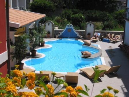 una grande piscina con scivolo e persone sedute intorno ad essa di Residence Hotel Villa Fiorentino a Città di Lipari