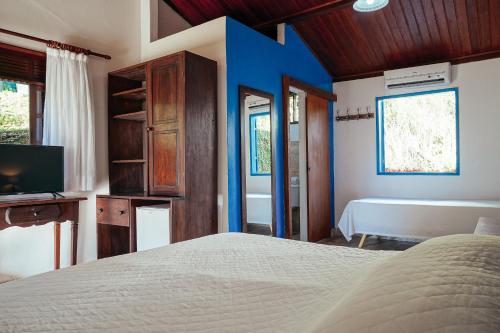a bedroom with a bed and a tv and a tub at Pousada Natureza in Morro de São Paulo