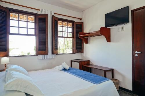a bedroom with a bed and a flat screen tv at Pousada Natureza in Morro de São Paulo