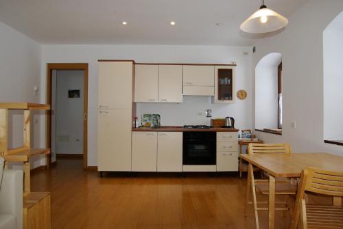 a kitchen with white cabinets and a table and a dining room at SAURISapar KHLEMELE in Sauris