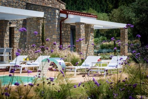 a garden with white chairs and a pool at Avista Private Resort in Vourvourou