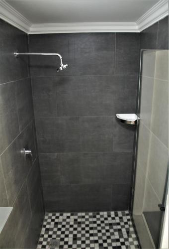 a bathroom with a shower with a tiled floor at Mahem Manor Guesthouse in Brits